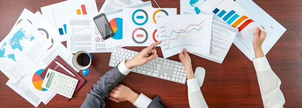 Sales manager and rep reviewing call statistics and prospecting results on printed reports at a desk.