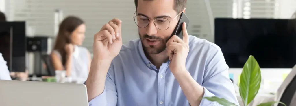 Sales professional making a phone prospecting call at a desk with notes and laptop in front of them.