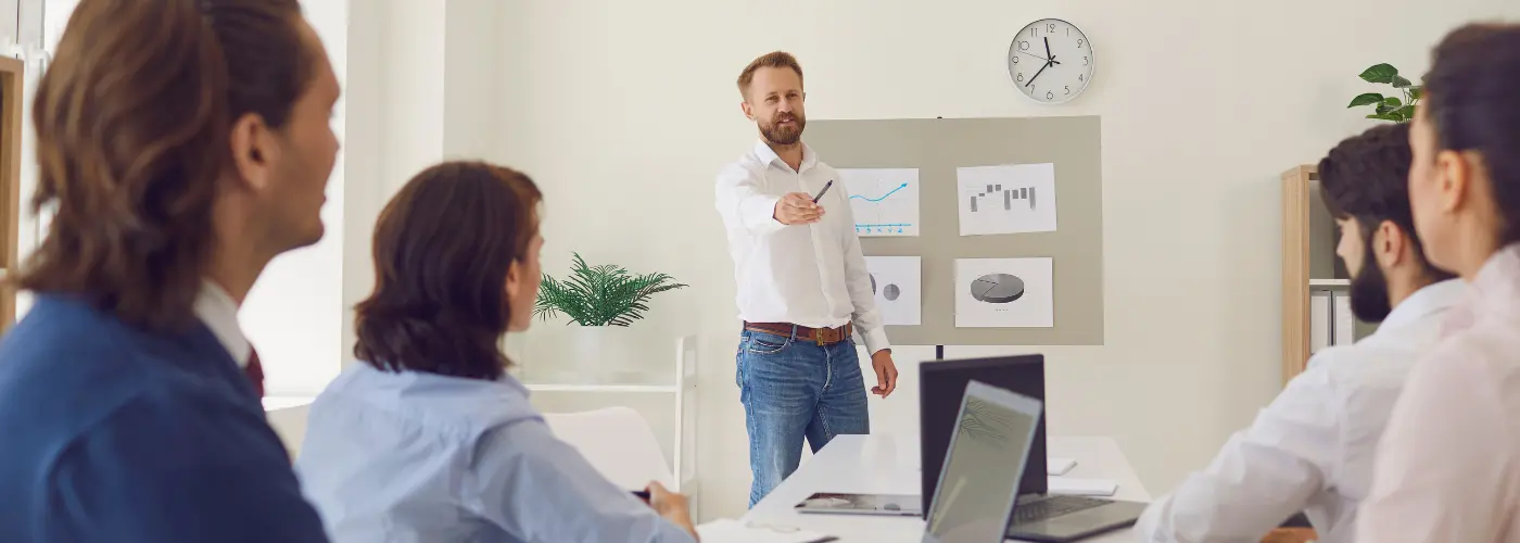 Sales manager and salespeople reviewing a structured repeatable sales process in a meeting room