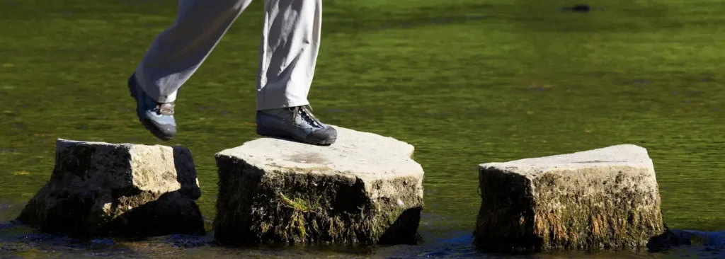 Stepping stones across water representing resilience and consistency required in daily sales prospecting